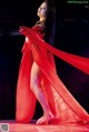 A woman in a red dress is dancing on a stage.