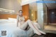 A naked woman sitting on a bed in a hotel room.