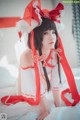 A woman in a red and white outfit sitting on a bed.