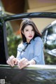 A woman leaning out the window of a black car.