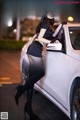 A woman leaning on the hood of a white car.