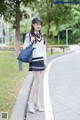 A woman in a school uniform is walking down the street.