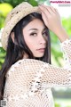 A woman wearing a straw hat is posing for a picture.