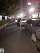 A woman walking down a street next to parked cars.