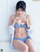 A woman in a blue bikini sitting on a white couch.