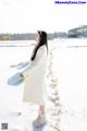 A woman in a white coat standing in the snow.