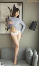 A woman in a gray shirt and white panties posing on a couch.