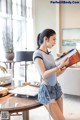 A woman in shorts and a t-shirt is reading a book.