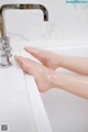 A woman's feet in a bathtub with a faucet.