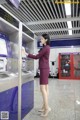 A woman in a purple suit is using an atm machine.