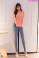 a woman in a pink top and jeans posing for a picture