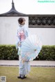 A woman in a blue and pink kimono holding an umbrella.