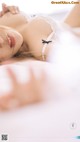 A woman laying on a bed in a white lingerie.