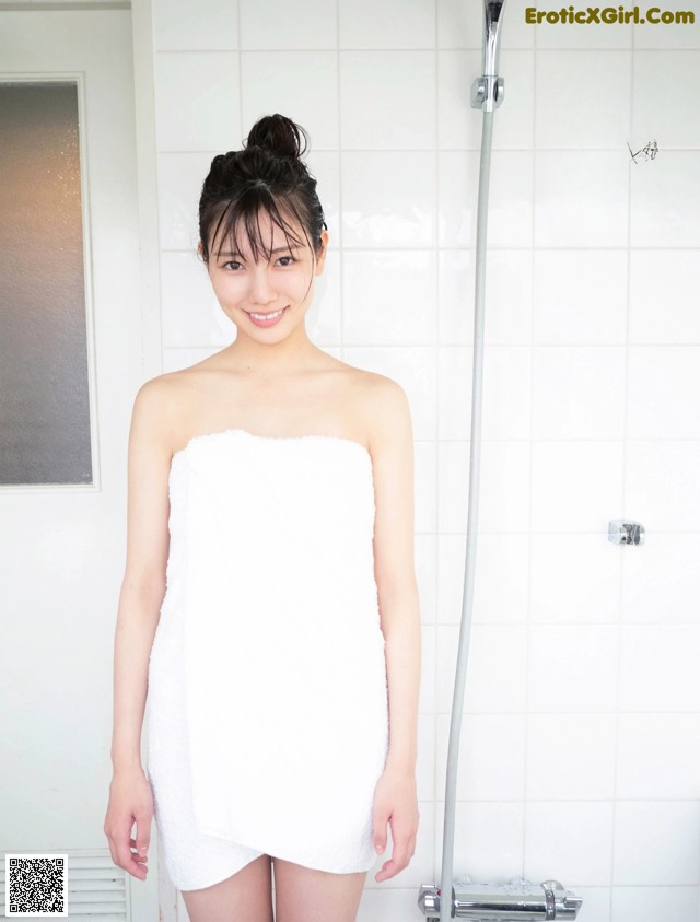 A woman in a white towel standing in a bathroom.