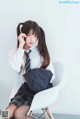 A woman sitting on a white chair wearing a school uniform.