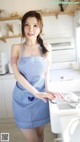 A woman in a blue and white apron standing in a kitchen.