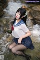 A woman in a sailor outfit sitting in a stream.