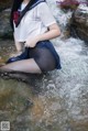 A woman in a school uniform is sitting in the water.