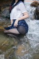 A woman in a school uniform is sitting in the water.