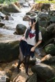 A woman in a school uniform standing in a stream.