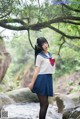 A woman in a school uniform standing in a stream.