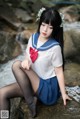 A woman in a sailor outfit sitting on a rock.