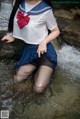 A woman in a sailor outfit is sitting in the water.