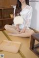 A woman sitting on the floor holding a fan.