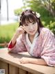 A woman in a pink kimono sitting on a wooden bench.