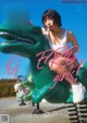 A woman sitting on top of a green dinosaur.