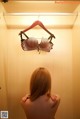 A woman standing in front of a closet with a bra hanging on a hanger.