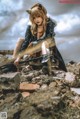 A woman sitting on top of a pile of rubble holding a gun.