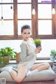 A woman sitting on a couch holding a potted plant.